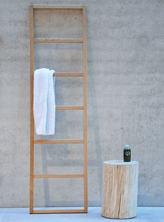 a white towel is hanging on a wooden ladder next to a toilet brush and soap dispenser