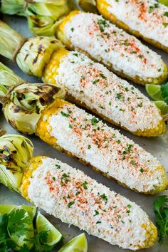 mexican street corn with limes and cilantro on the side