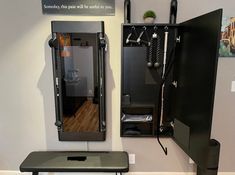 a bench and mirror in a room with white walls, wood flooring and black cabinets