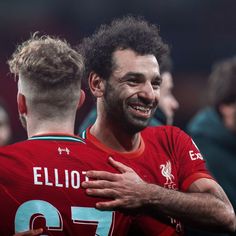 two soccer players are hugging each other in the middle of a game with others watching