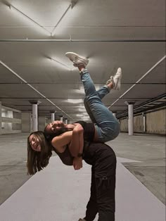 a man and woman are doing acrobatic tricks in an empty parking garage