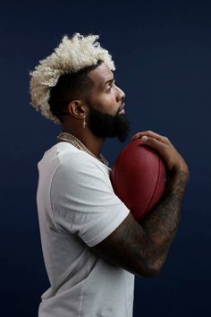 a man holding a basketball in his right hand and wearing a mohawk on top of it