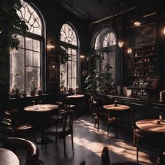 a dimly lit restaurant with large windows and wooden tables in the center, surrounded by potted plants