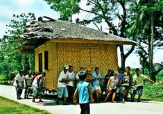 a group of people standing in front of a small hut on the side of a road