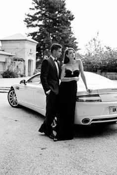 a man and woman standing next to a white car