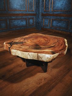 a wooden table sitting on top of a hard wood floor next to a blue wall