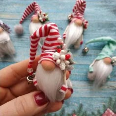 a hand holding a small gnome ornament in front of other ornaments on a table