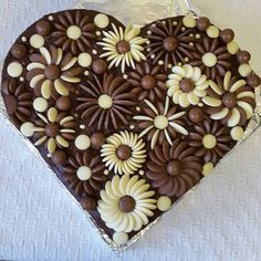 a heart shaped chocolate cake with white and brown decorations