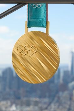 a gold medal hanging from a metal bar in front of a large cityscape