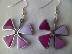 two pairs of purple and pink flower shaped earrings on white fabric background with silver earwires