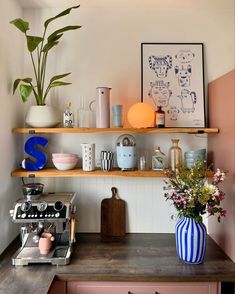 a kitchen counter topped with lots of shelves filled with pots and vases next to a coffee maker