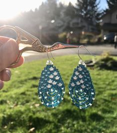 "\"Gentle Rain\" earrings remind us of the power of gentleness when we're caught in a storm. These take form as a raindrop, with an internal scene of translucent raindrops blossoming into flowers. Design features numerous faceted Labradorite gemstones that refract subtle rainbows of light, and encourage spiritual transformation, intuition, mental clarity and protection. Finished with elegant sterling silver ear-hooks. Including ear-hook, measures 2.5\" long, 1.25\" wide. Order includes inspirati Turquoise Teardrop Earrings With Faceted Beads, Beaded Teardrop Crystal Earrings, Teardrop Beaded Earrings For Jewelry Making, Artisan Teardrop Earrings With Dangling Beads, Teardrop Beaded Earrings With Faceted Beads, Handmade Unique Teardrop Earrings, Unique Handmade Teardrop Beaded Earrings, Teardrop Earrings With Faceted Beads For Gifts, Unique Teardrop Beaded Earrings