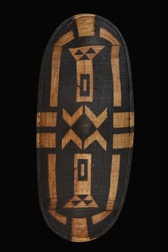 an african mask with geometric designs on the front and back side, in black background