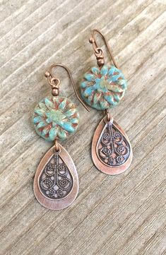 Boho earrings with blue floral Czech glass and antiques copper filigree dangles.Blue green Czech glass beads with a carved floral pattern give these earrings a rustic bohemian vibe. The glass is accented perfectly by warm, antiqued copper filigree teardrops. Very light weight and a perfect gift idea for any nature lover.Product overview:- Made with carved, floral Czech glass and antiqued copper- Very light weight and versatile- Hypoallergenic ear wires Branding Palette, Essential Jewelry, Necklaces Ideas, Silver Jewelry Box, Jewelry Blue, Bohemian Earrings, Blue Jewelry, Flower Jewelry, Floral Jewellery