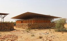 an outdoor shelter made out of wood and stone in the middle of a desert area