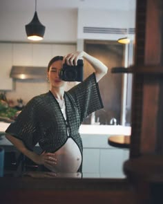 a pregnant woman taking a selfie with her camera