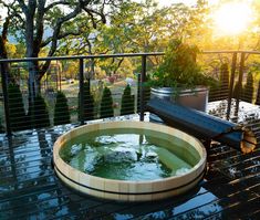 a hot tub sitting on top of a wooden deck next to a tree filled forest