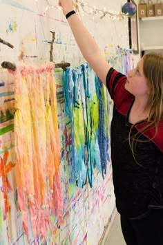 a woman is painting on the wall with her hands