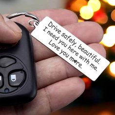 a hand holding a car keychain that says drive safely, i need you here with me love you now