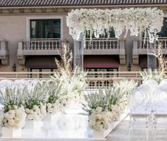 an outdoor wedding setup with white flowers and greenery in front of a large building