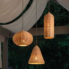 three wicker lamps hanging from the ceiling over a table with flowers and greenery in the background