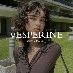 a woman sitting on top of a grass covered field next to a tall building with the words vesperine over it