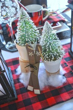 two potted trees are sitting on a red and black checkered tablecloth with snow flakes