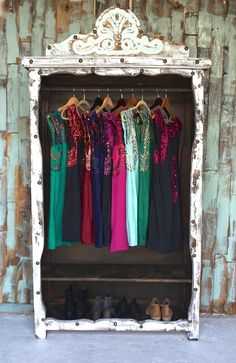 an old wooden cabinet with clothes hanging on it