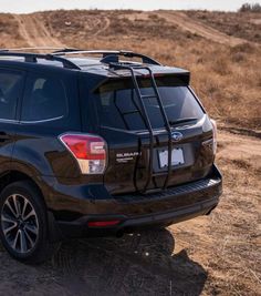 the back end of a black subarunt parked on a dirt road