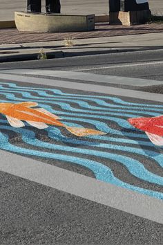 there are two fish painted on the street with blue and orange stripes in it's center