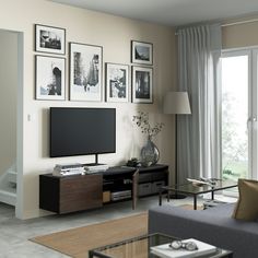 a living room with pictures on the wall and a television in front of a window