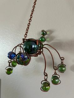 a metal spider with green and blue glass beads hanging from it's back end