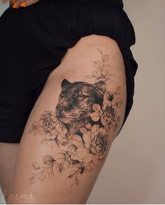 a woman's thigh with a cat and flowers tattoo on her leg, which is black and white