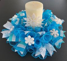 a blue and white wreath with a lit candle on the top is sitting on a table