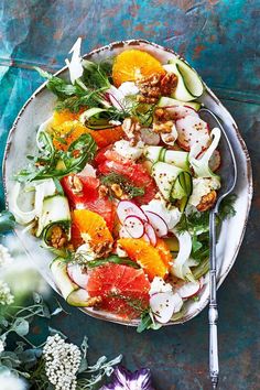 a white plate topped with lots of different types of vegetables and fruit on top of a blue table cloth