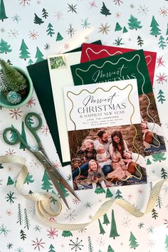 christmas cards and scissors on a table with wrapping paper