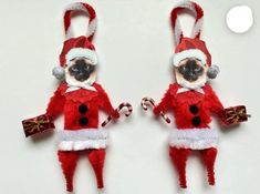 two red and white stuffed animals wearing santa claus outfits with candy canes in their hands