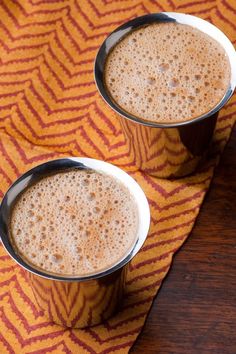 two metal cups filled with liquid sitting on top of a table