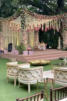 an outdoor wedding setup with chairs and flowers on the stage, surrounded by greenery