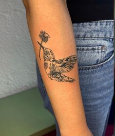 a woman's arm with a bird and flower tattoo on the left side of her arm