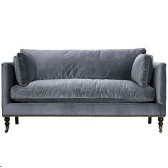 a gray velvet couch with two pillows on the back and one arm upholstered