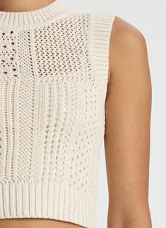 the back of a woman's cropped top with holes in white knitted fabric