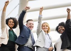 four business people raising their arms in the air