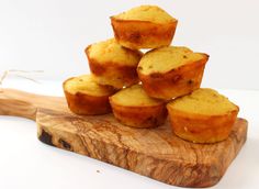 small muffins stacked on top of each other on a wooden cutting board next to a piece of wood