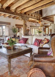 a living room filled with furniture and lots of wooden beams on top of it