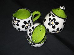 three green and white ceramic teapots with matching saucers on a black background