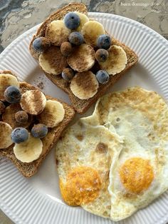 two pieces of toast with blueberries and bananas on them are sitting on a plate