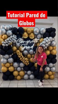 a woman standing in front of a giant balloon wall with gold and silver balloons on it