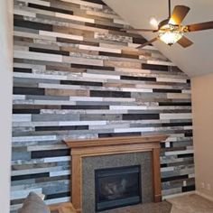 a living room with a fireplace, ceiling fan and striped wall paper on the walls