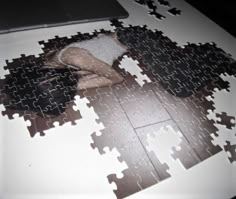 a woman laying on top of a white table covered in jigsaw puzzles